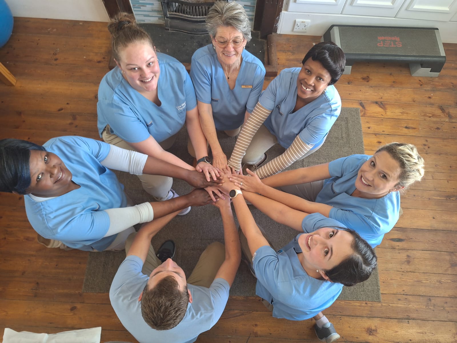 The Ludolf & Lienkie Physiotherapists team with hands together in a huddle